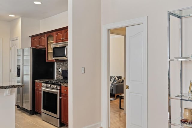 kitchen featuring dark stone countertops, light wood-type flooring, stainless steel appliances, and tasteful backsplash