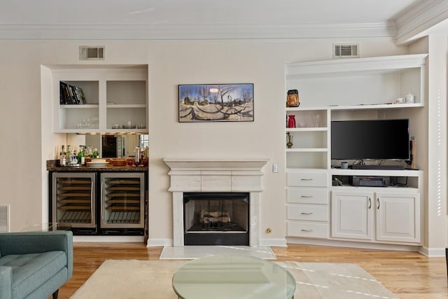 living room featuring bar, light hardwood / wood-style flooring, wine cooler, and ornamental molding