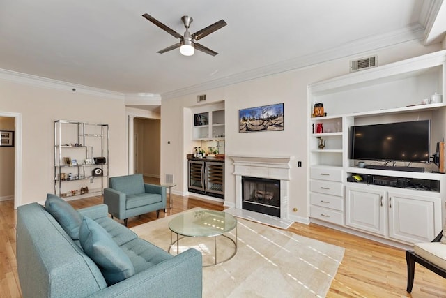 living room featuring bar, light hardwood / wood-style floors, ceiling fan, and ornamental molding