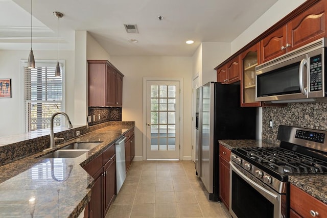 kitchen featuring plenty of natural light, sink, stainless steel appliances, and decorative light fixtures