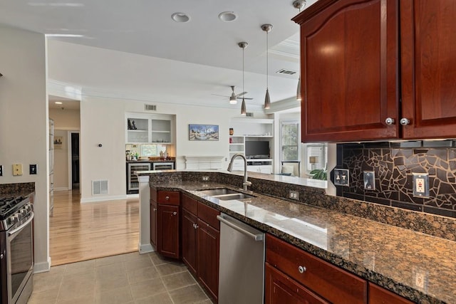 kitchen with sink, stainless steel appliances, beverage cooler, dark stone countertops, and pendant lighting