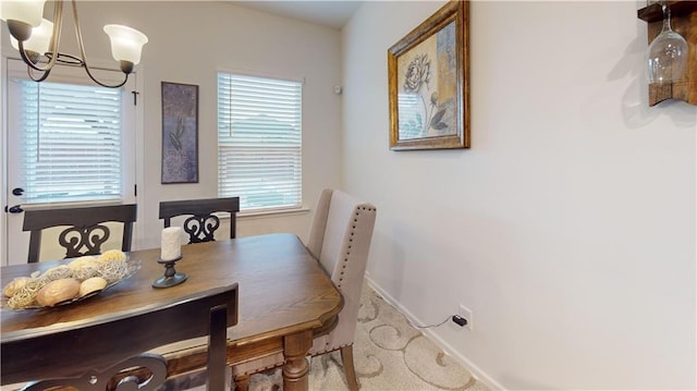 carpeted dining area with baseboards and a notable chandelier