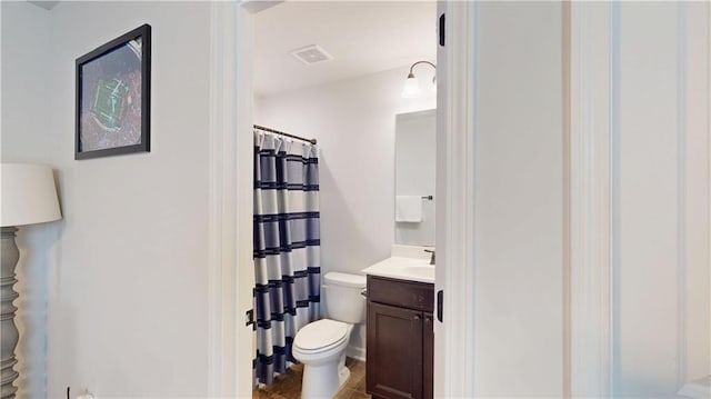 full bathroom featuring a shower with shower curtain, visible vents, vanity, and toilet