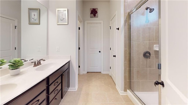 bathroom featuring double vanity, baseboards, tile patterned floors, a shower stall, and a sink