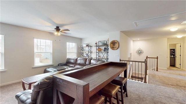 interior space featuring baseboards, a ceiling fan, and light colored carpet