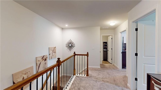 hall with light carpet, baseboards, and an upstairs landing