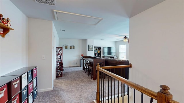 corridor with attic access, baseboards, visible vents, carpet flooring, and an upstairs landing