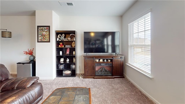 carpeted living area featuring visible vents and baseboards