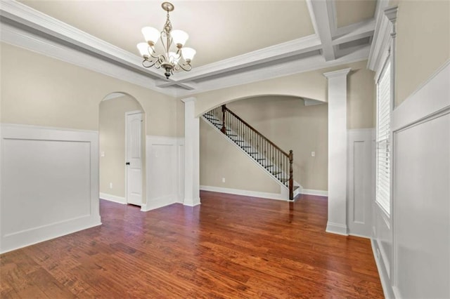 spare room featuring arched walkways, coffered ceiling, stairway, dark wood-style flooring, and a notable chandelier