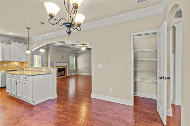 kitchen featuring a center island, arched walkways, pendant lighting, and white cabinets