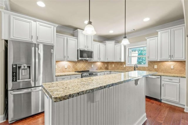 kitchen featuring appliances with stainless steel finishes, a center island, white cabinetry, and decorative light fixtures