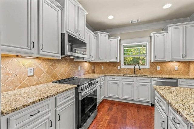 kitchen with stainless steel appliances, a sink, visible vents, white cabinets, and crown molding