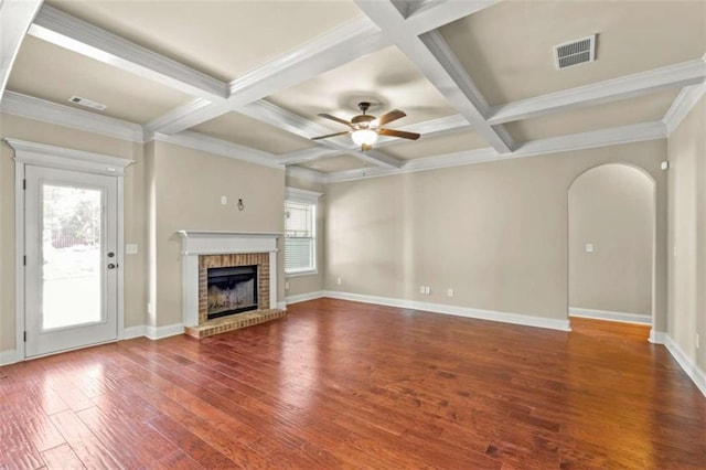 unfurnished living room featuring a brick fireplace, visible vents, arched walkways, and wood finished floors