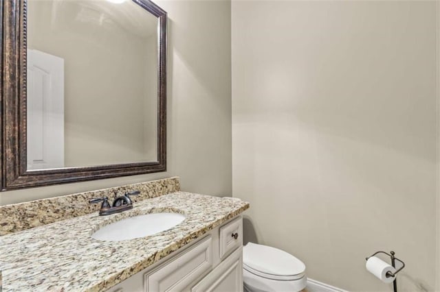 bathroom featuring baseboards, vanity, and toilet