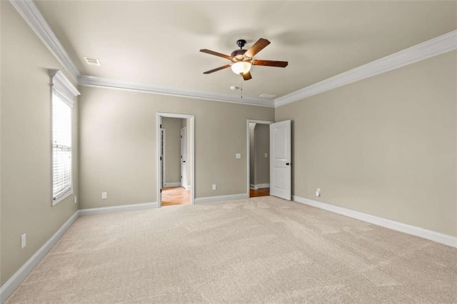 empty room featuring light carpet, visible vents, baseboards, a ceiling fan, and ornamental molding