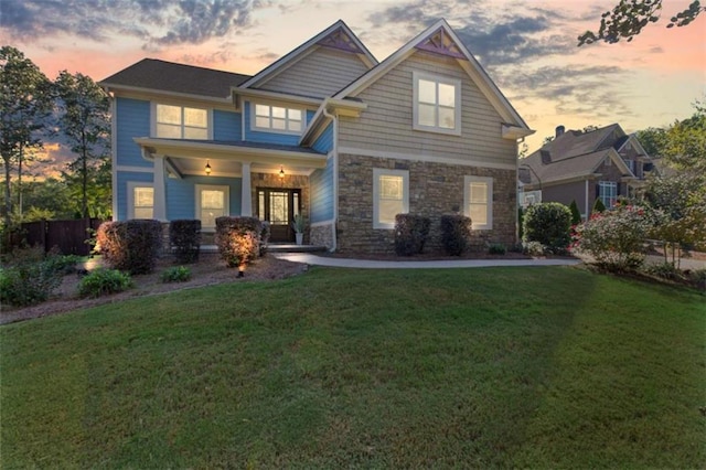 craftsman-style home with stone siding and a yard