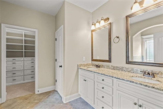 full bath featuring a sink, double vanity, tile patterned flooring, and a walk in closet