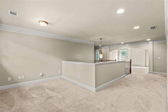 empty room featuring light carpet, visible vents, arched walkways, and recessed lighting