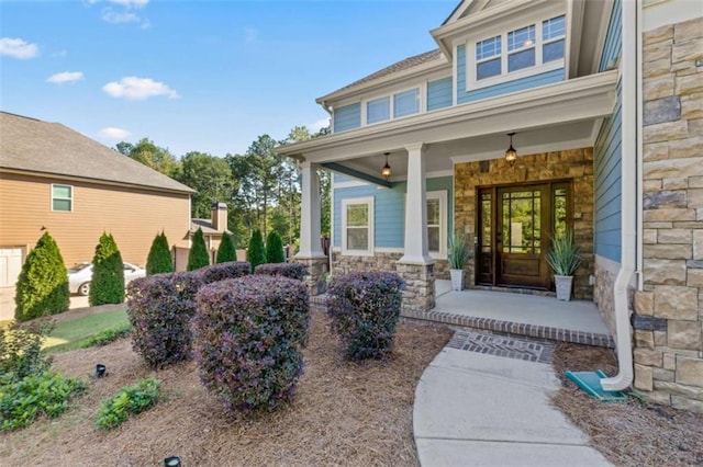 doorway to property with stone siding and a porch