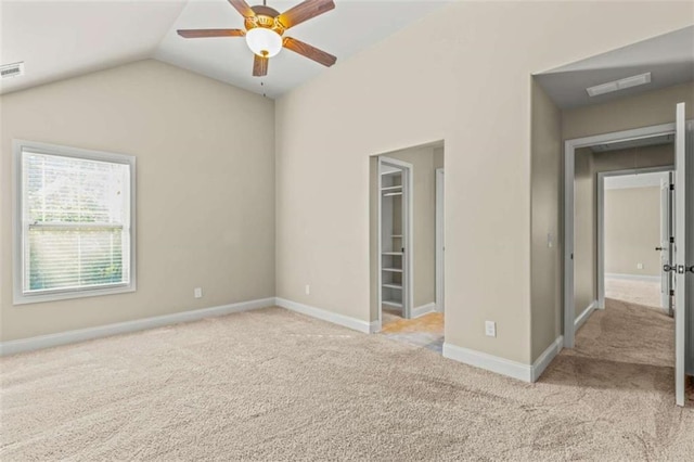 spare room with visible vents, baseboards, a ceiling fan, light colored carpet, and vaulted ceiling