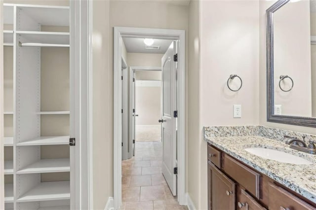 full bathroom with a spacious closet, vanity, and tile patterned floors