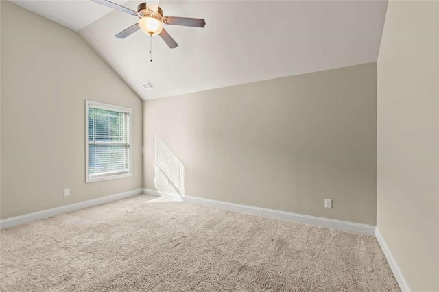 carpeted empty room featuring lofted ceiling, ceiling fan, visible vents, and baseboards