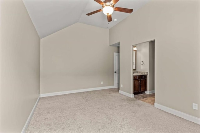 unfurnished bedroom with lofted ceiling, light colored carpet, ensuite bathroom, a ceiling fan, and baseboards