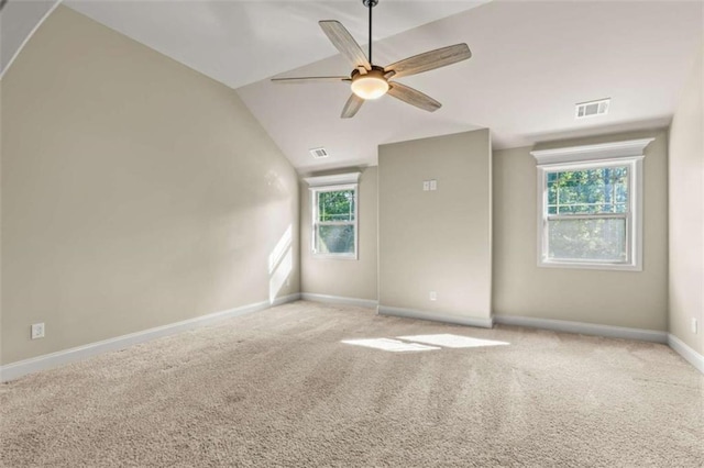 empty room with vaulted ceiling, baseboards, visible vents, and light colored carpet