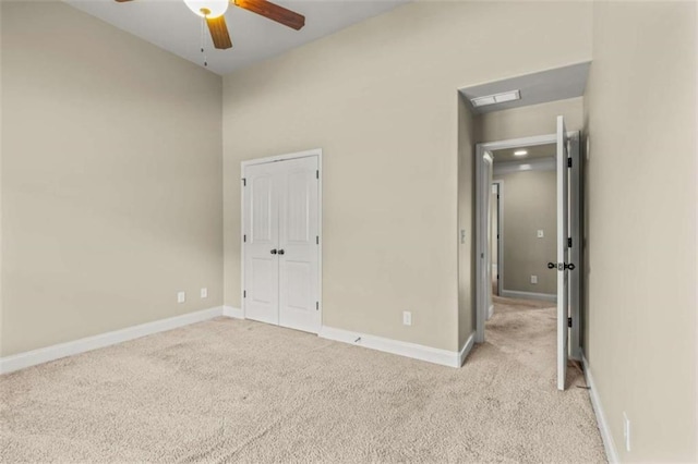 unfurnished bedroom with baseboards, ceiling fan, a closet, and light colored carpet