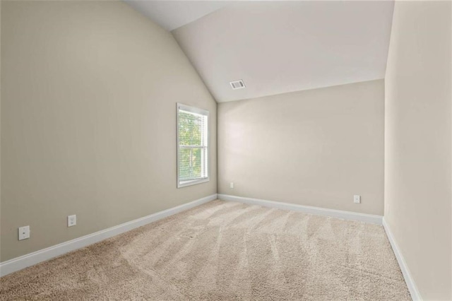 carpeted spare room featuring visible vents, vaulted ceiling, and baseboards