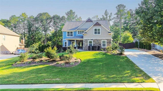 craftsman inspired home with stone siding, fence, a front lawn, and concrete driveway