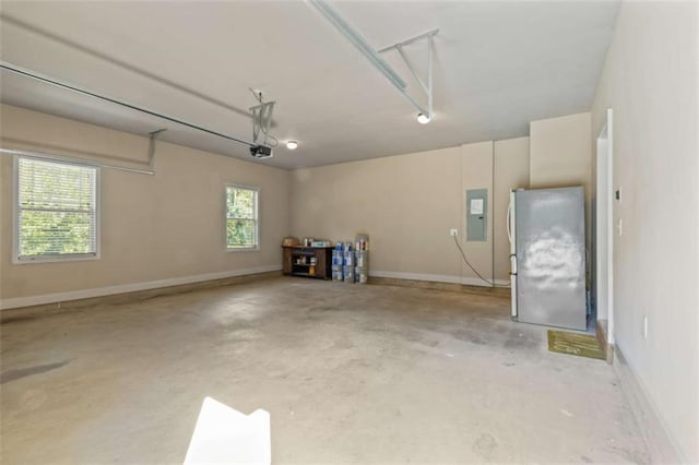 garage featuring electric panel, baseboards, a garage door opener, and freestanding refrigerator