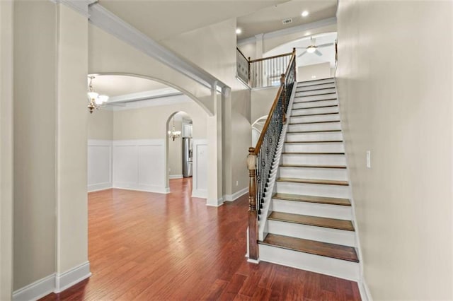 stairway with baseboards, arched walkways, wood finished floors, a notable chandelier, and recessed lighting