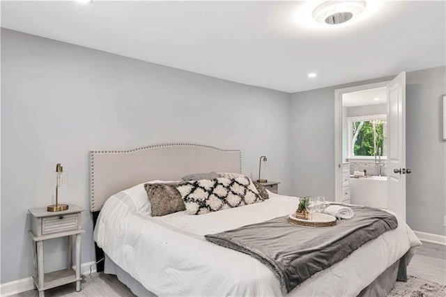 bedroom featuring ensuite bathroom and light hardwood / wood-style floors