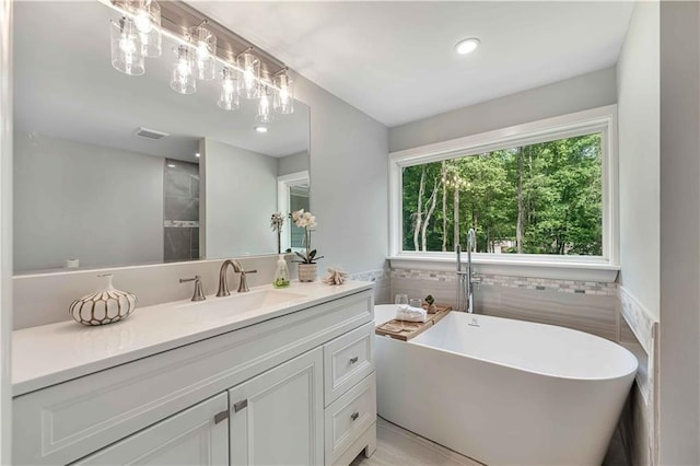 bathroom with vanity, a bathing tub, and tile walls