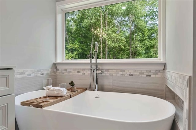 bathroom featuring tile walls, a bath, and a wealth of natural light