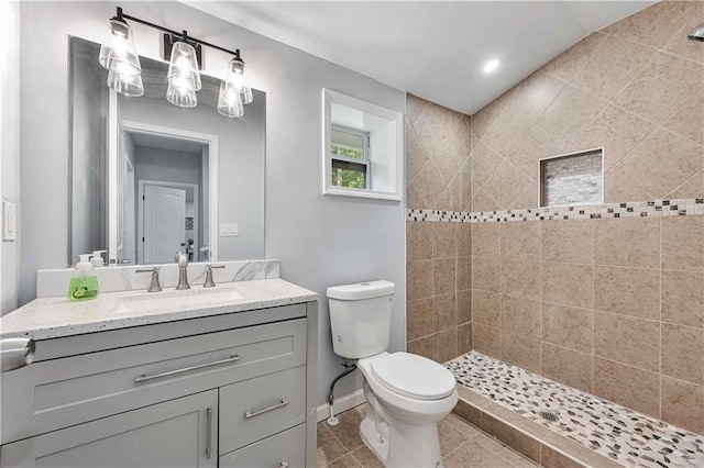 bathroom with vanity, tile patterned flooring, toilet, and a tile shower