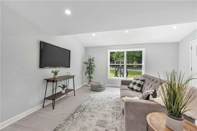 living room featuring lofted ceiling and light hardwood / wood-style floors