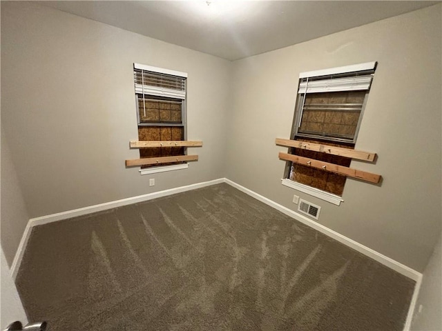 spare room featuring dark colored carpet