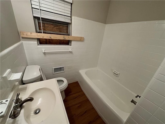 bathroom featuring a bath, toilet, tile walls, hardwood / wood-style flooring, and sink