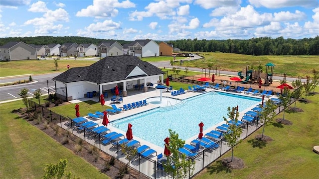 community pool with a lawn, a patio, a residential view, fence, and playground community