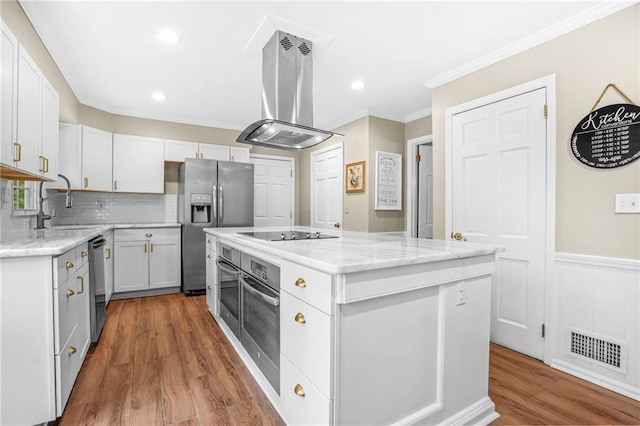 kitchen with island exhaust hood, white cabinetry, visible vents, appliances with stainless steel finishes, and a kitchen island