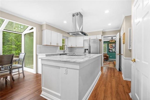 kitchen featuring a center island, stainless steel fridge, crown molding, island range hood, and black electric stovetop