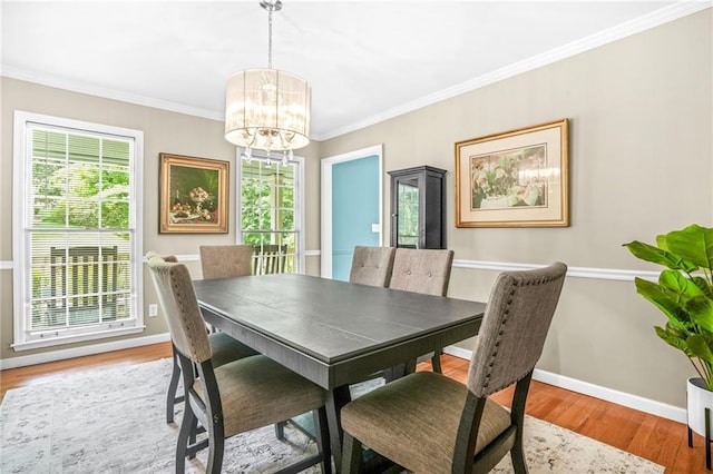 dining area with a chandelier, ornamental molding, baseboards, and wood finished floors