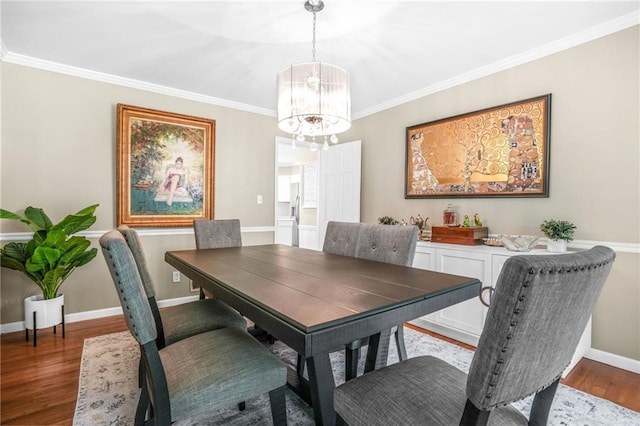 dining area with baseboards, ornamental molding, a chandelier, and wood finished floors