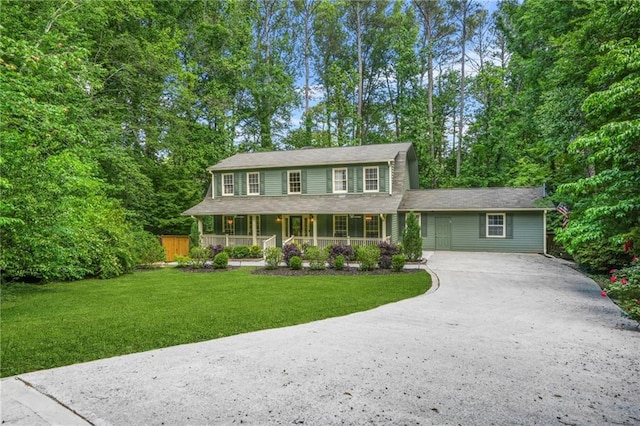 colonial house featuring concrete driveway, a porch, and a front yard