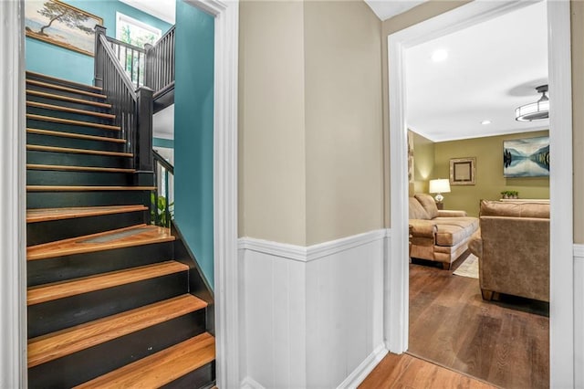 staircase with wainscoting, recessed lighting, and wood finished floors
