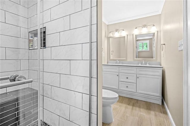 bathroom featuring double vanity, tiled shower, ornamental molding, and a sink