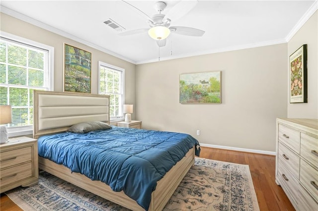 bedroom featuring wood finished floors, visible vents, baseboards, ceiling fan, and ornamental molding