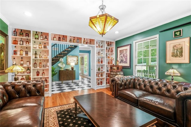 living area featuring stairway, crown molding, wood finished floors, and built in shelves